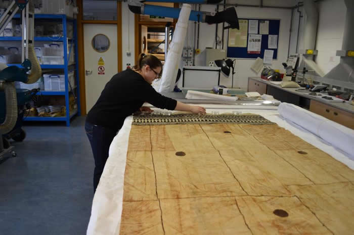 Kirstie Williams conserving barkcloth for the upcoming exhibition